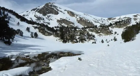 High altitude human settlement Pyrenees rock shelter overlooking snow-covered valley